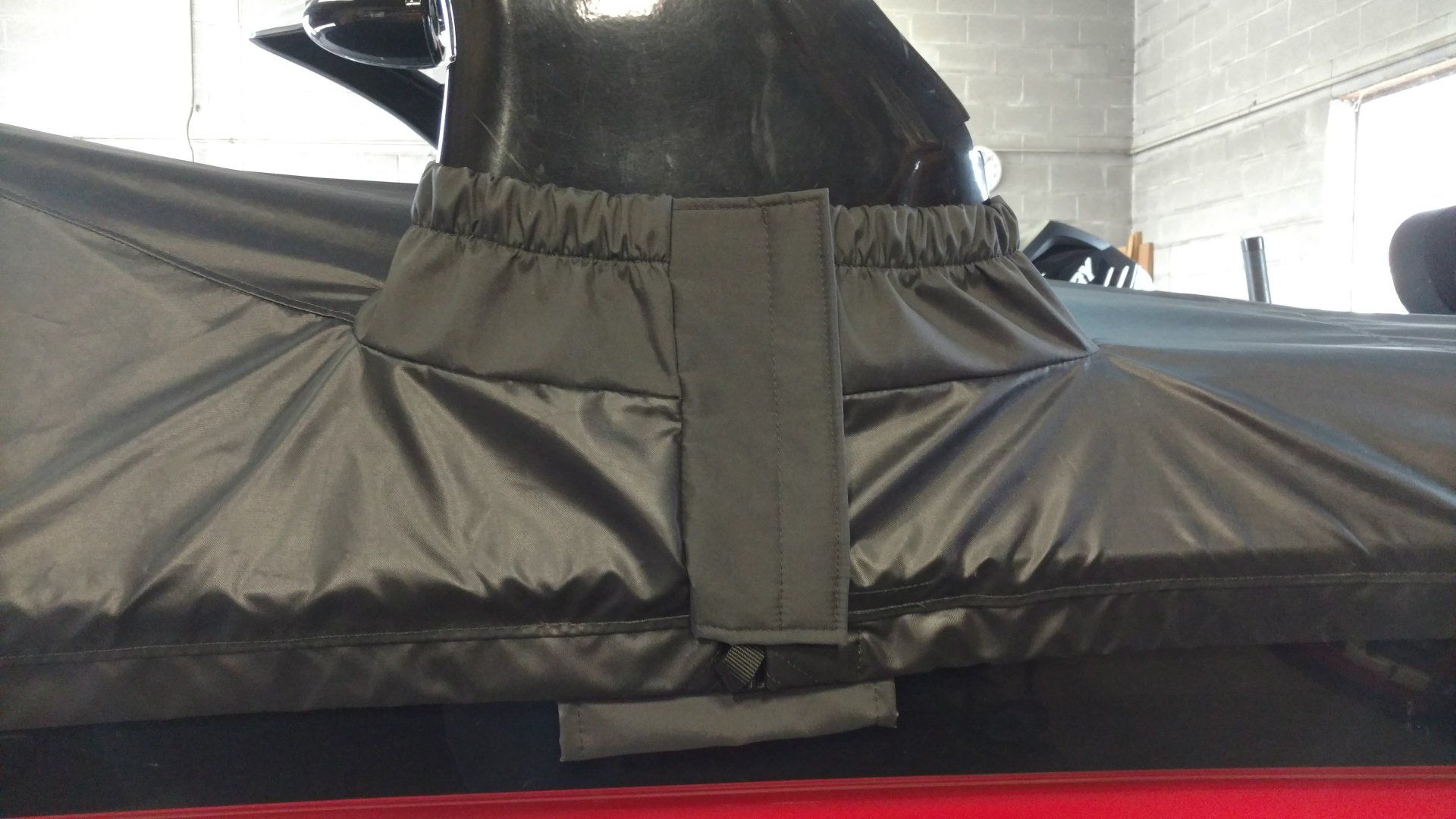 A black tarp is covering a boat in a garage.