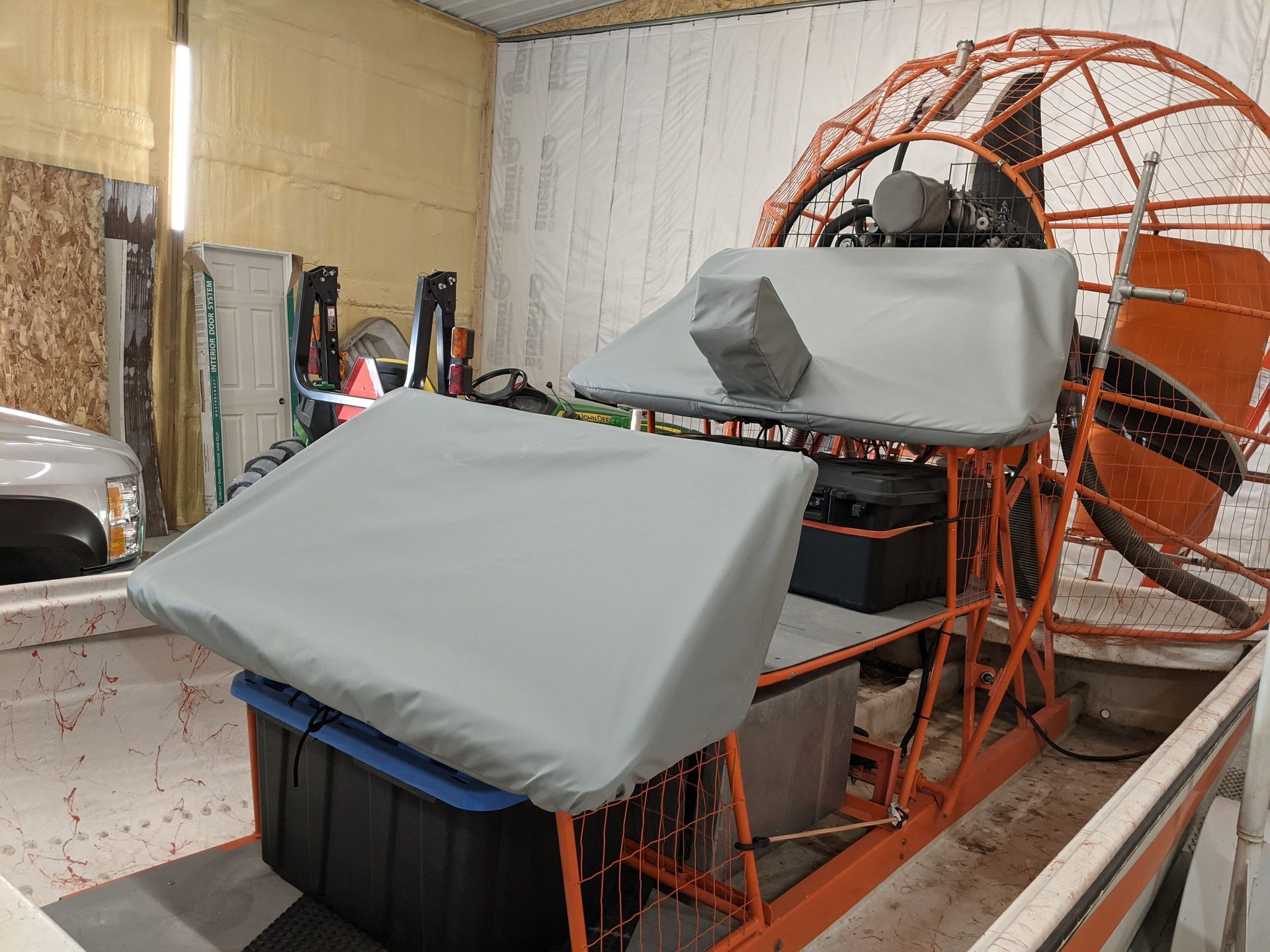 A boat with a cover on it is sitting in a garage.