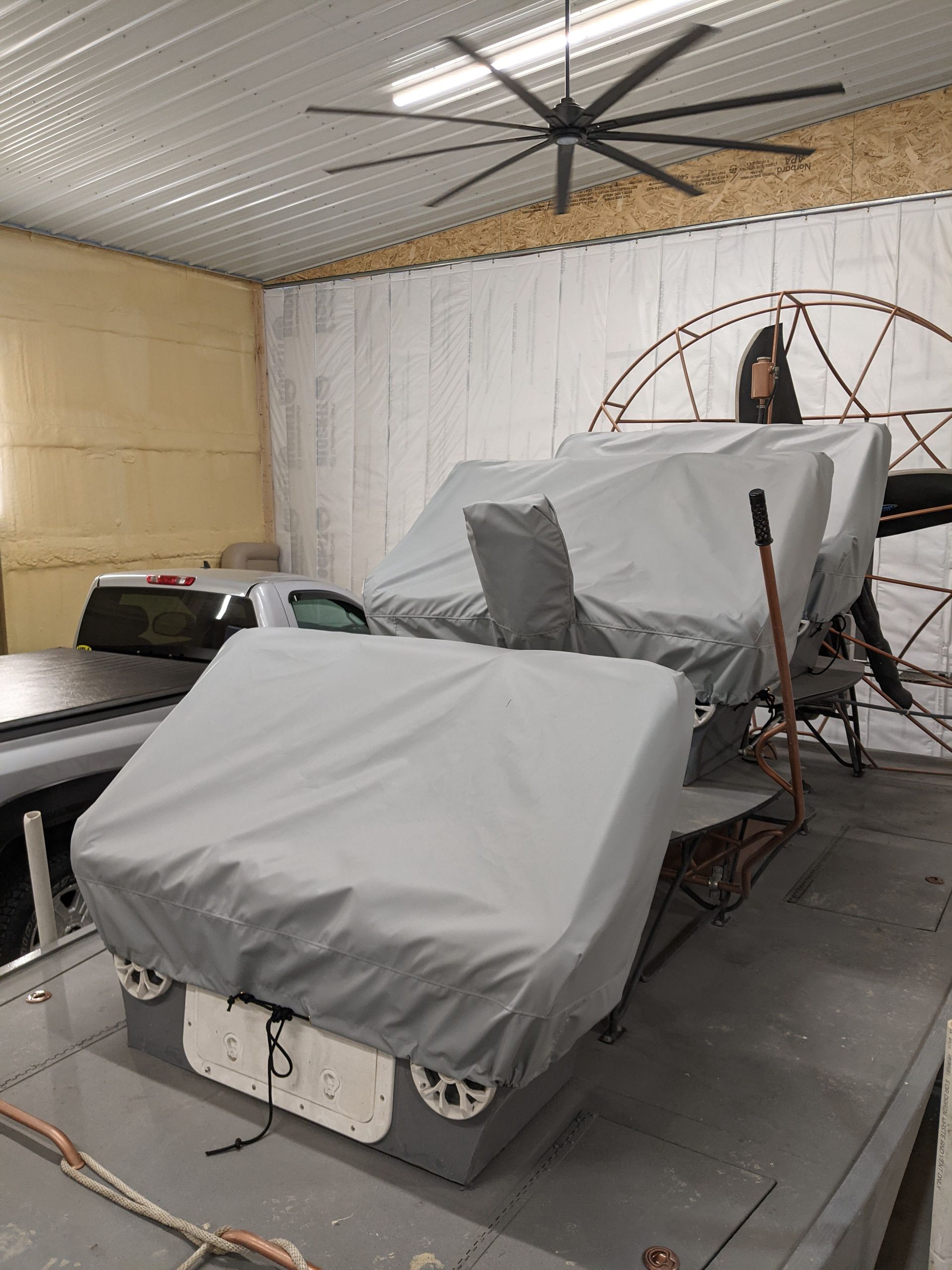 A boat with a cover on it is sitting in a garage.