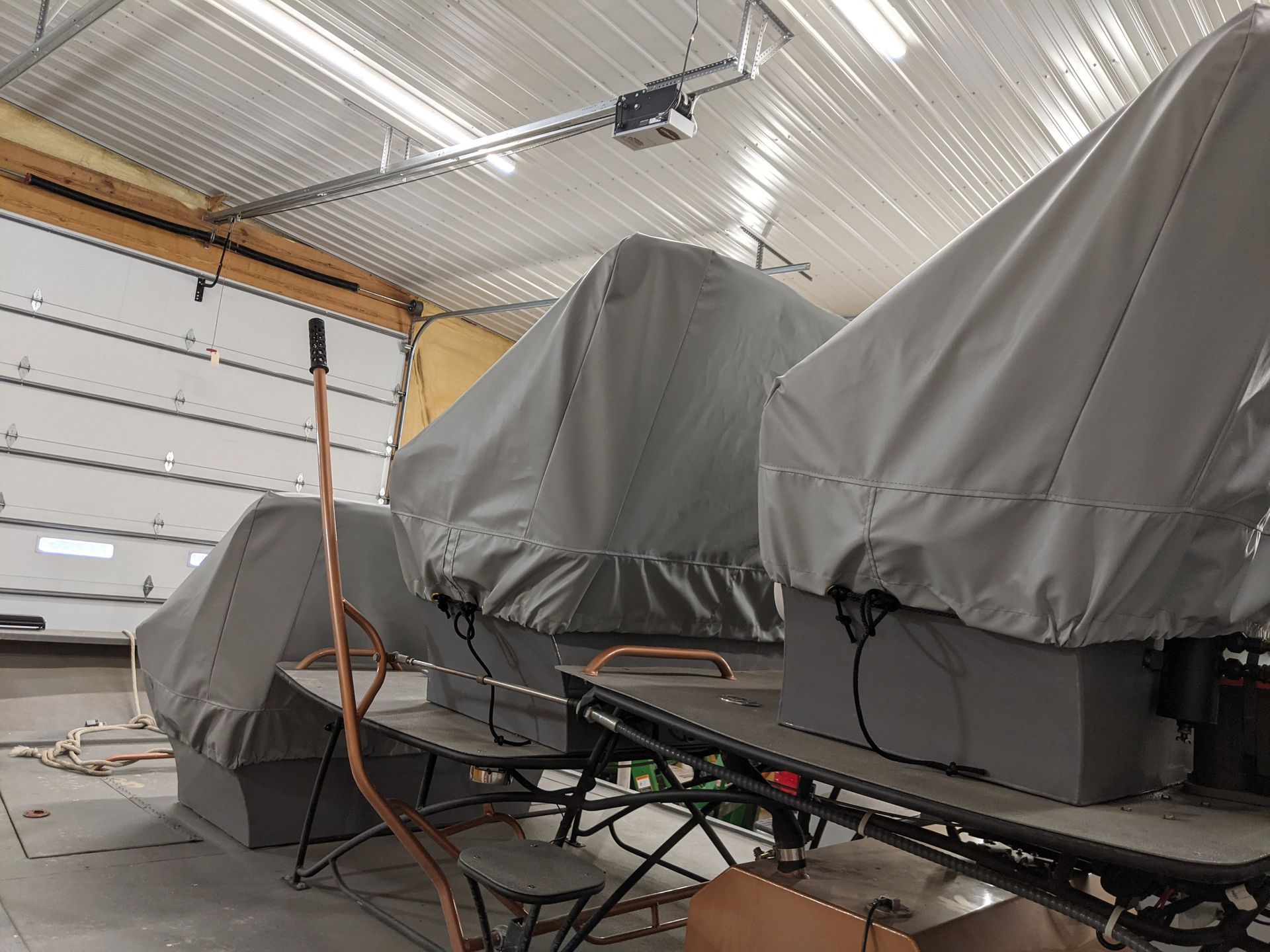 A boat with a cover on it is sitting in a garage.