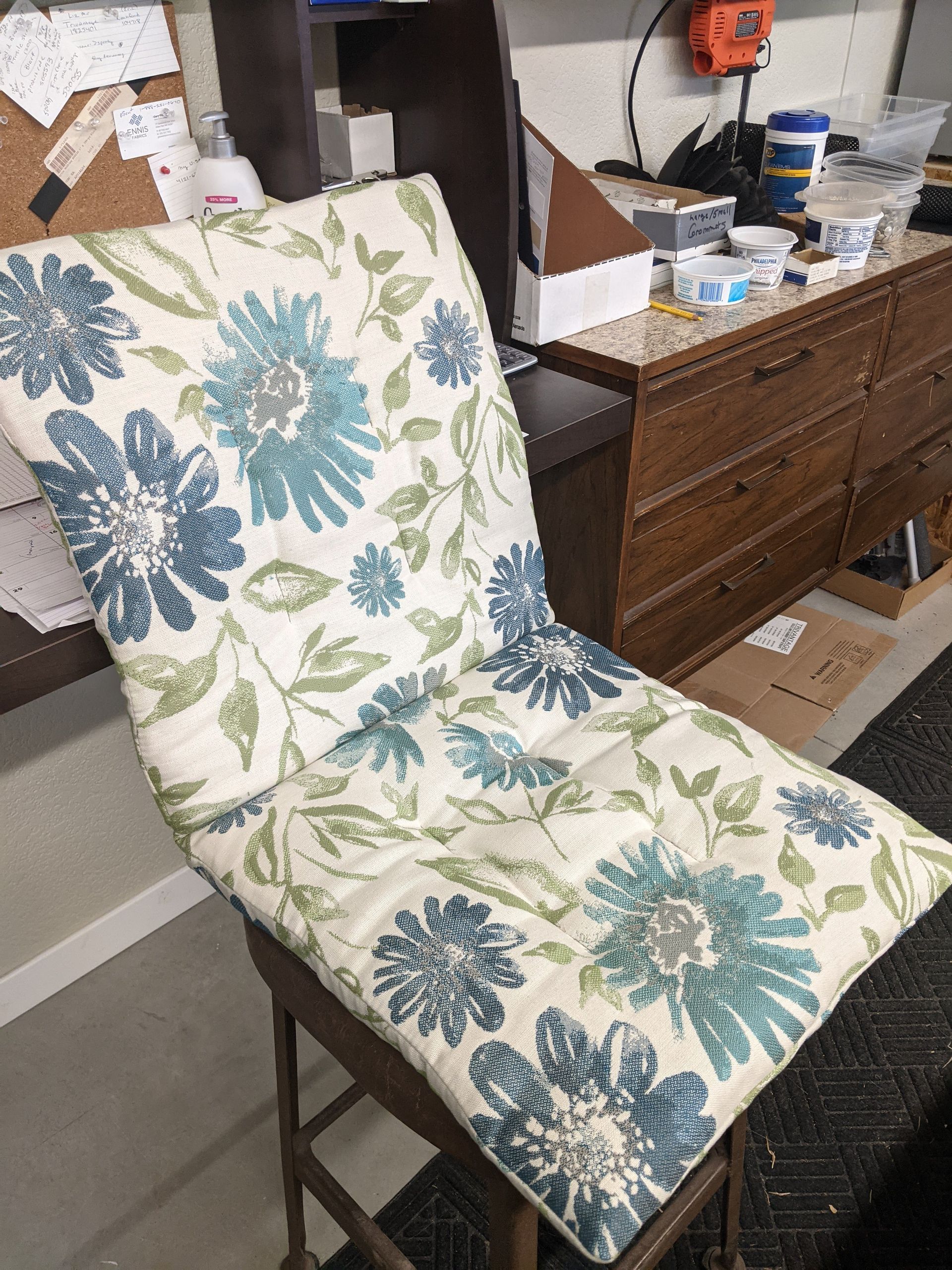 A chair with a blue and green floral cushion on it.