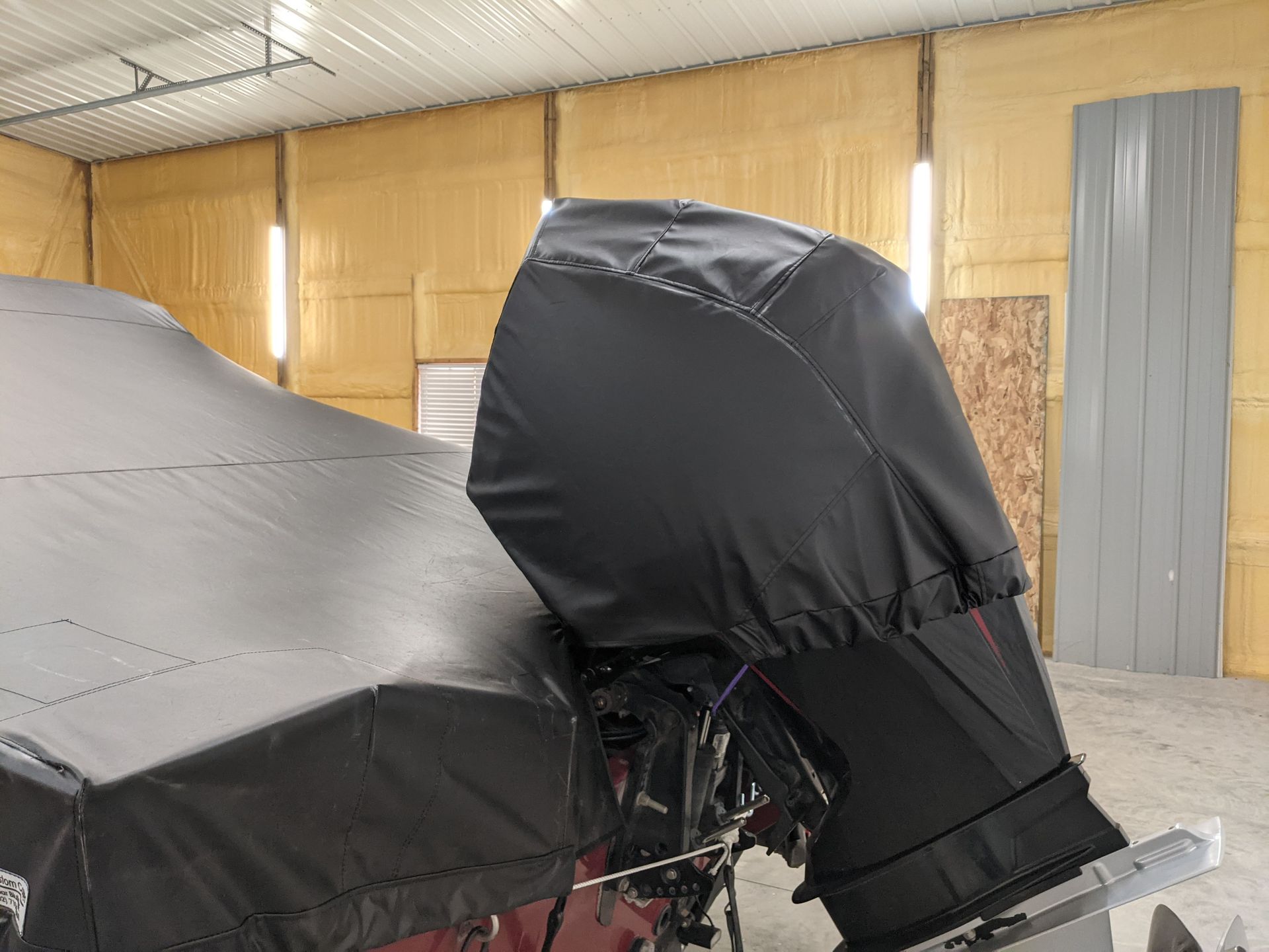 A boat with a black cover on it is sitting in a garage.