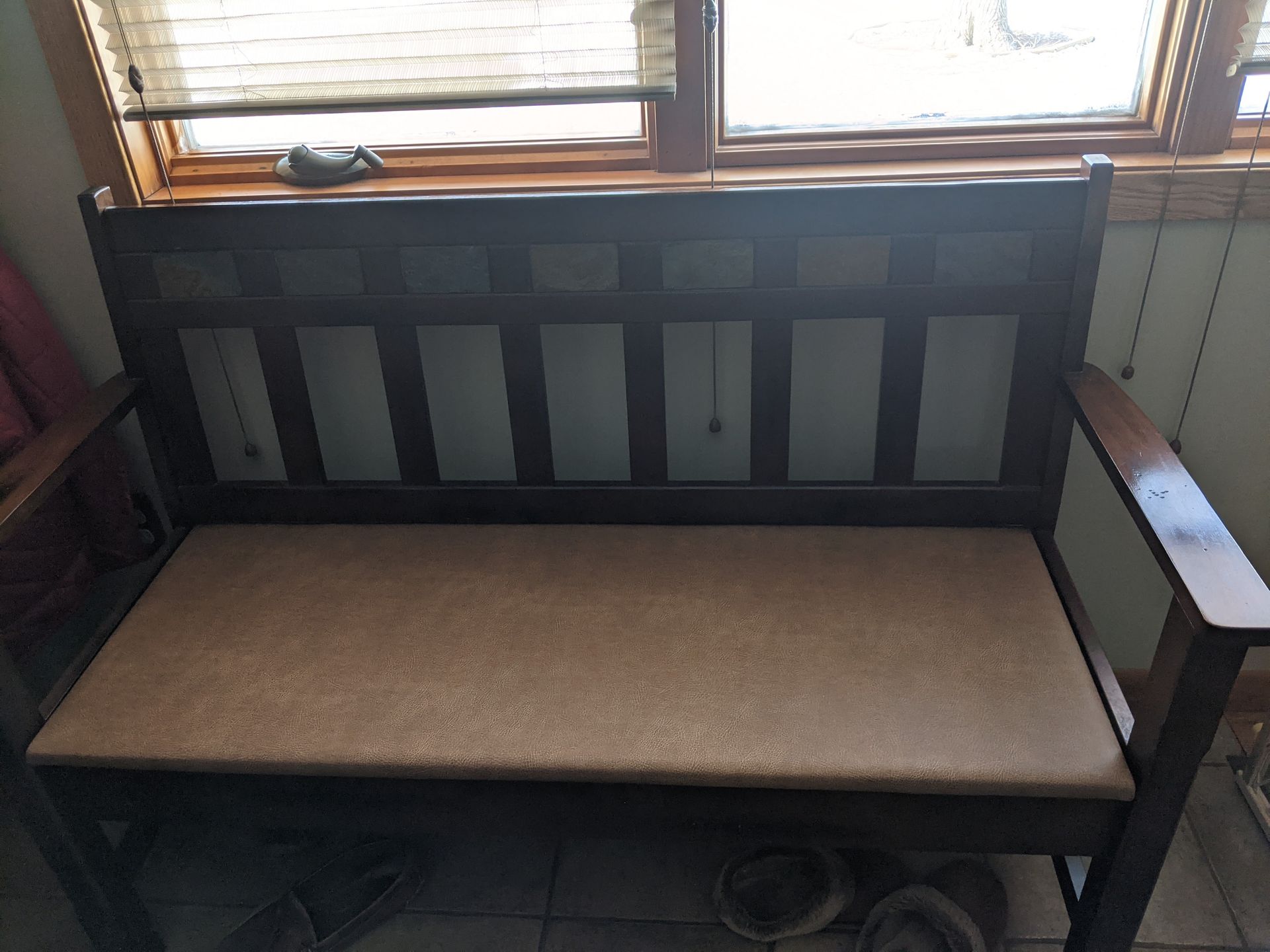 A wooden bench is sitting in front of a window.