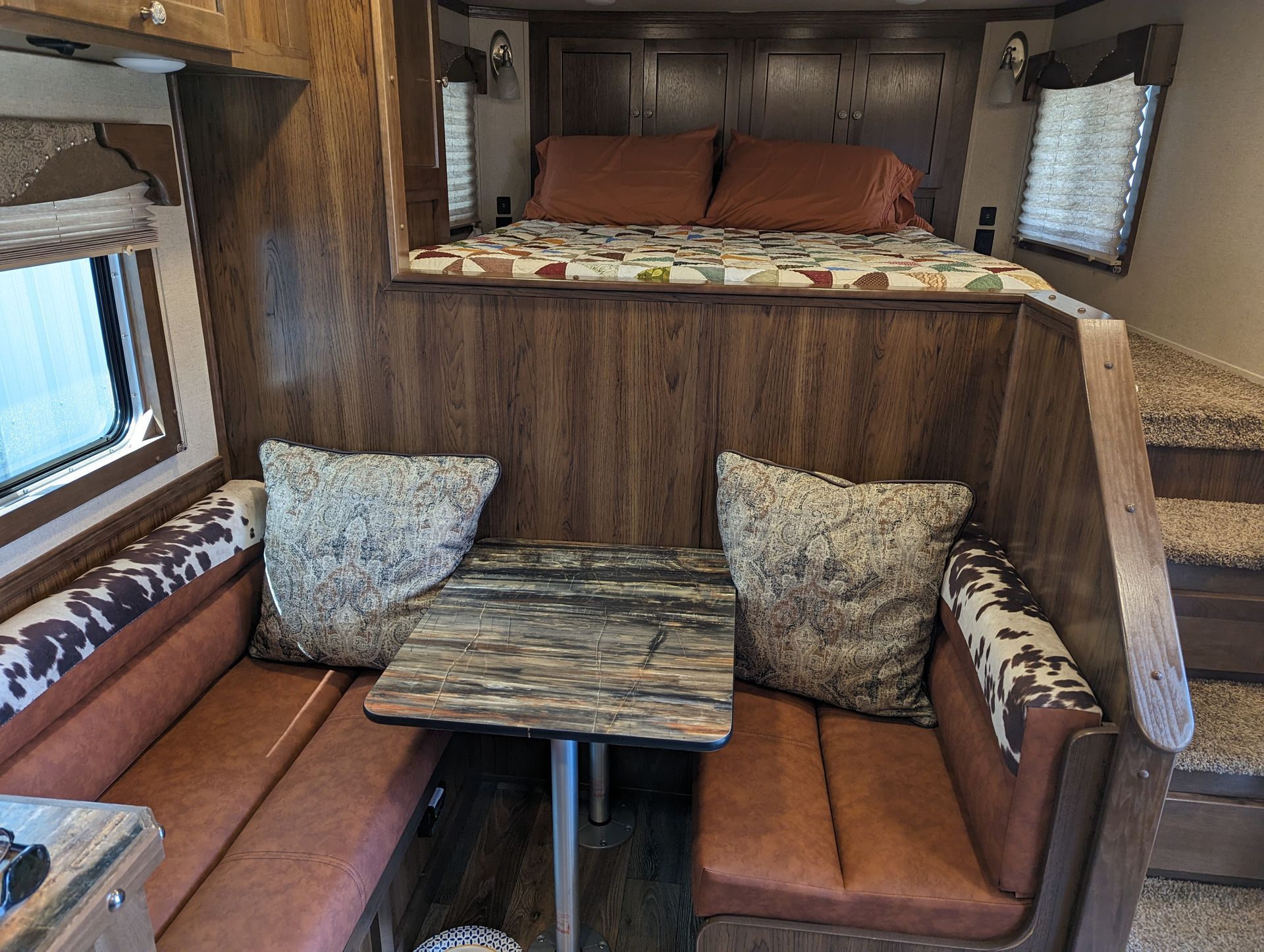 A rv with a bed and a table in it.