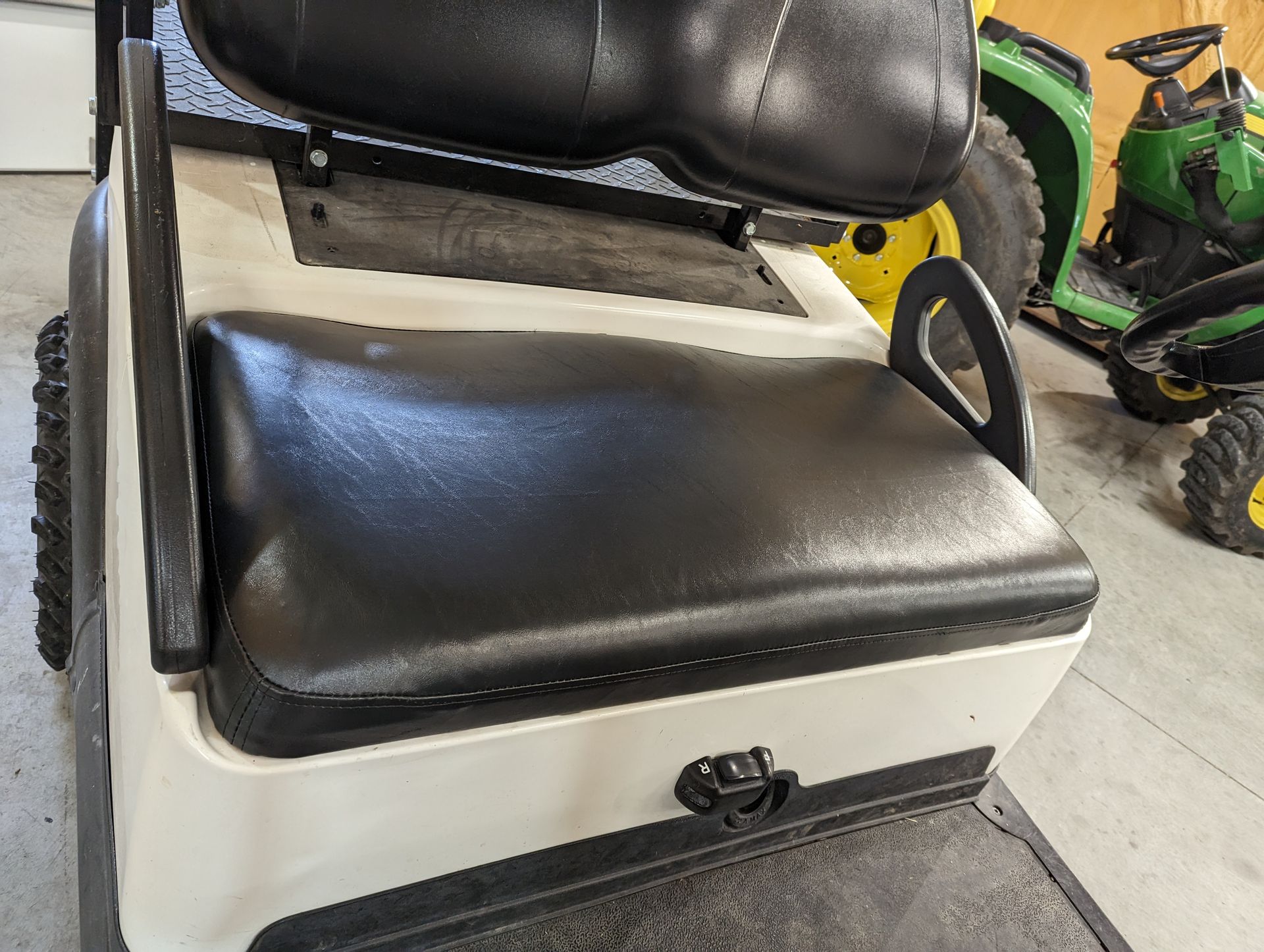 A black and white golf cart with a green tractor in the background