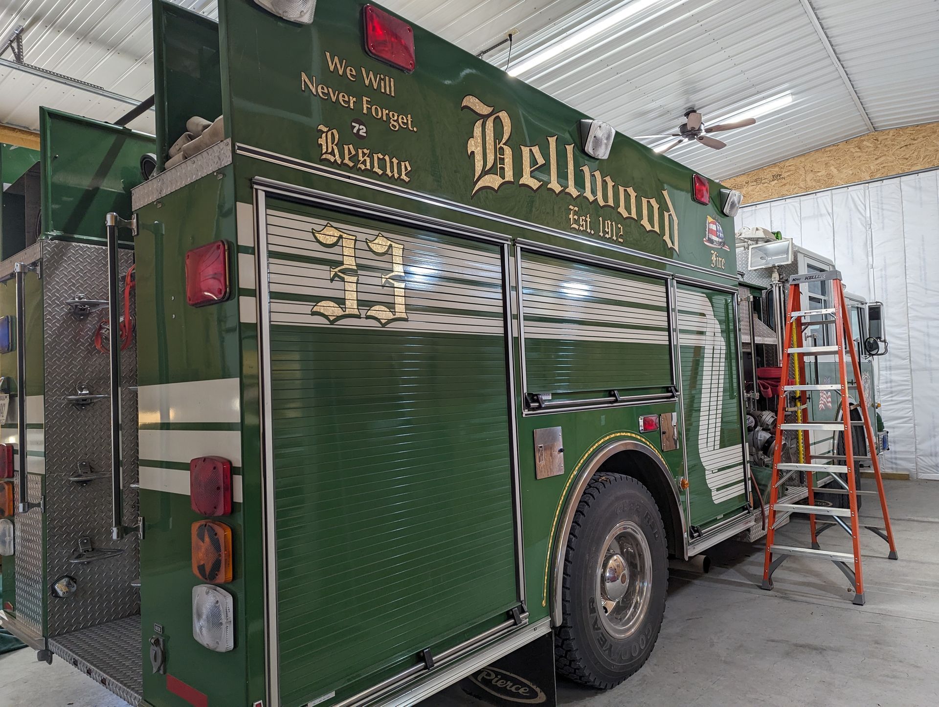 A green bellwood fire truck is parked in a garage.