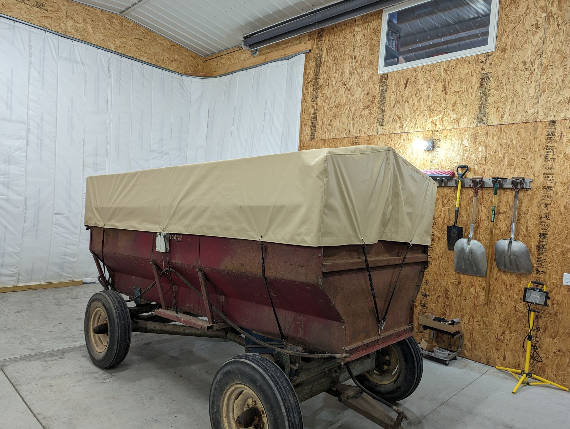 A wagon with a cover on it is sitting in a garage.