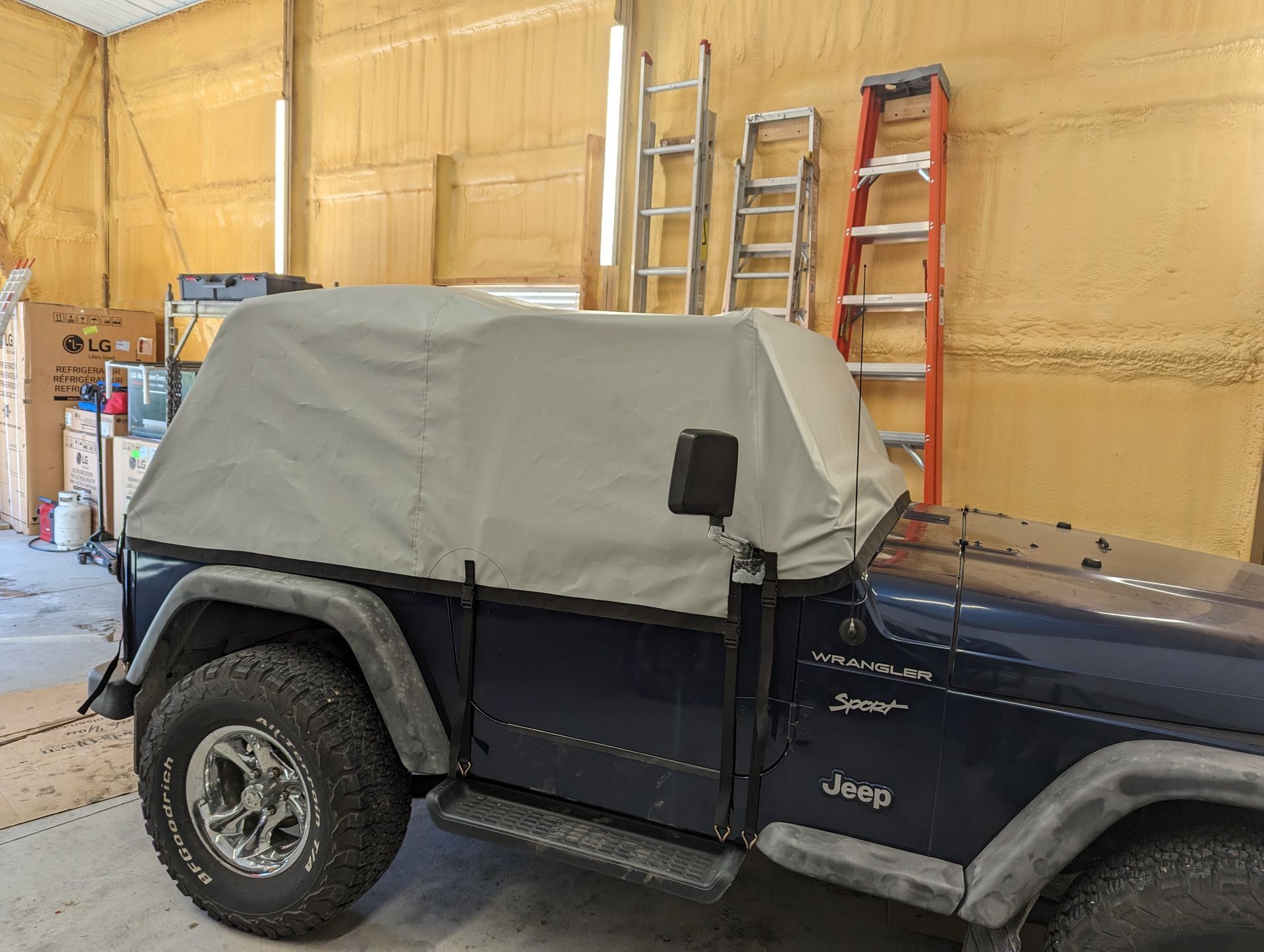 A jeep with a canopy on top of it is parked in a garage.