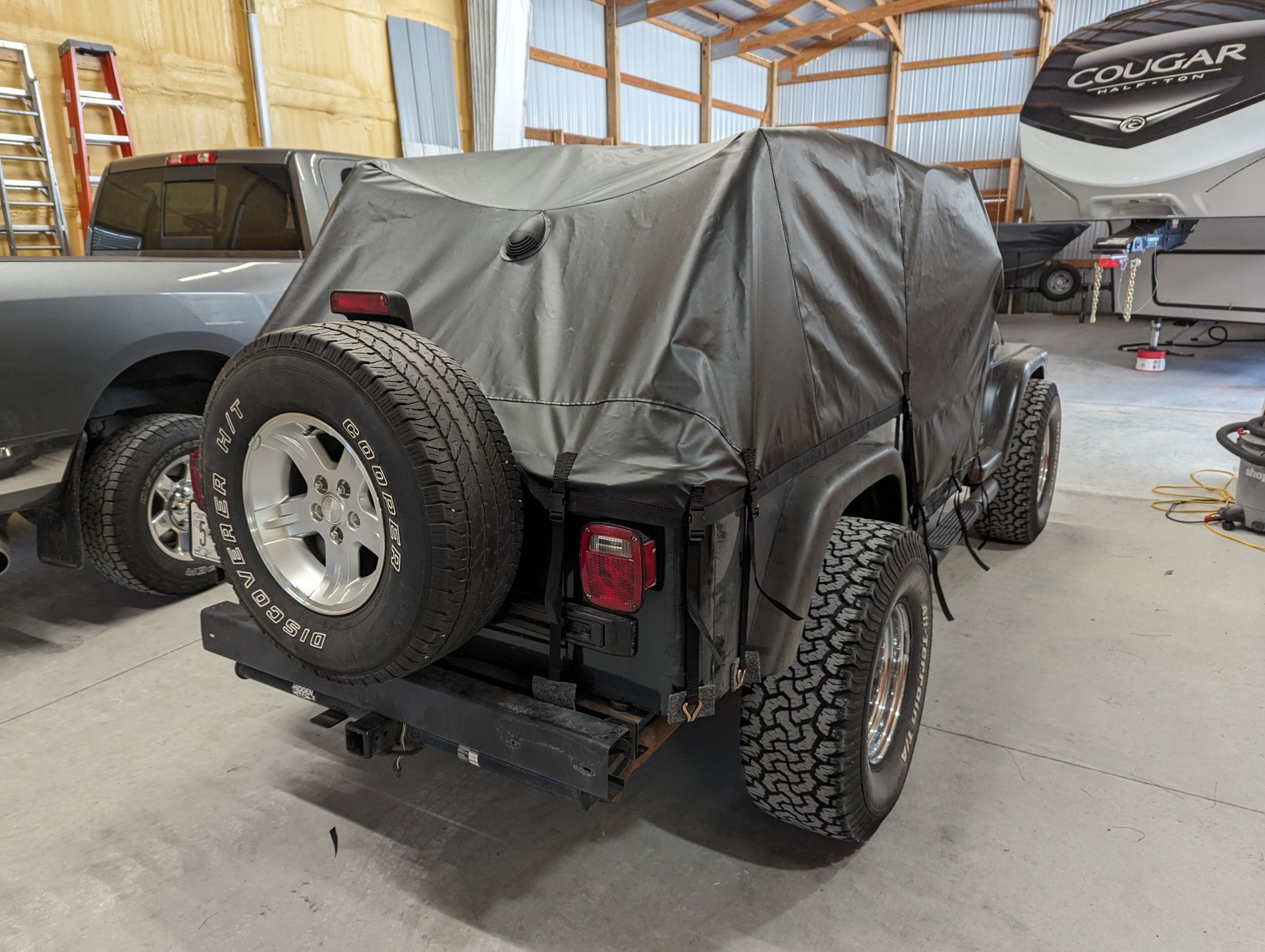 A jeep with a cover on it is parked in a garage.