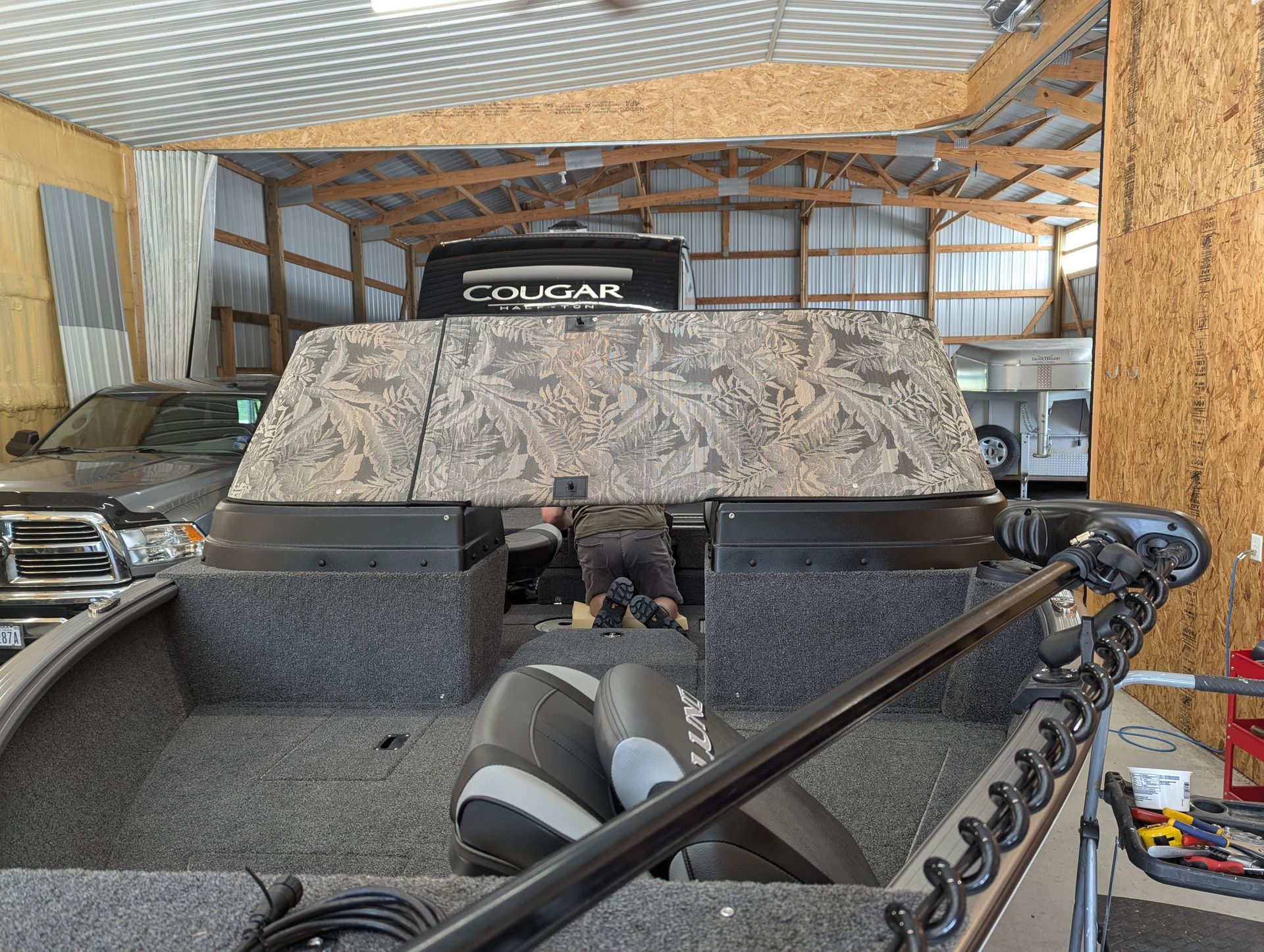 A cougar truck is parked in a garage next to a boat.