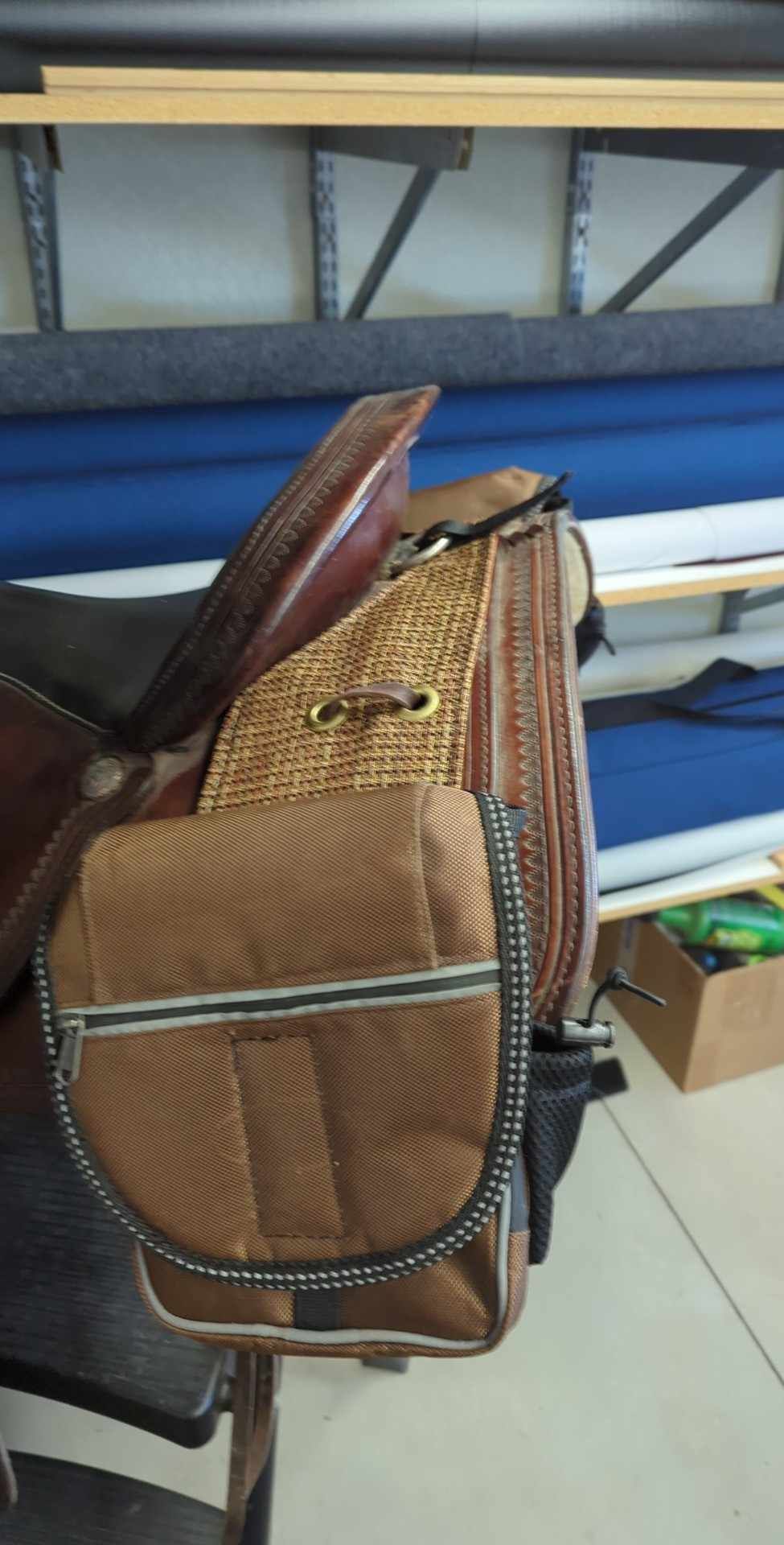 A brown bag is sitting on top of a brown saddle.