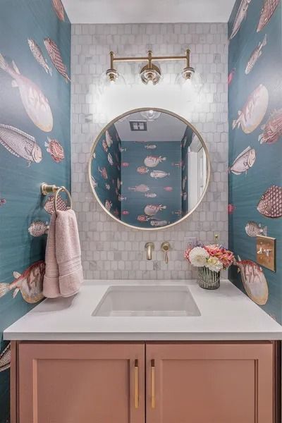 Bathroom with coral cabinets, a round mirror, and fish-patterned wallpaper.