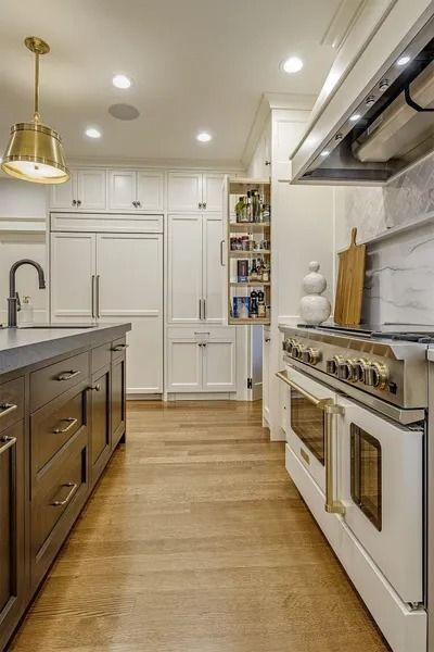 Luxury kitchen with white cabinets, wood floors, and a large stove.