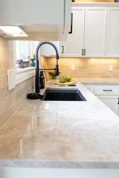 Kitchen with a black sink, faucet, white cabinets, and a light-colored countertop.
