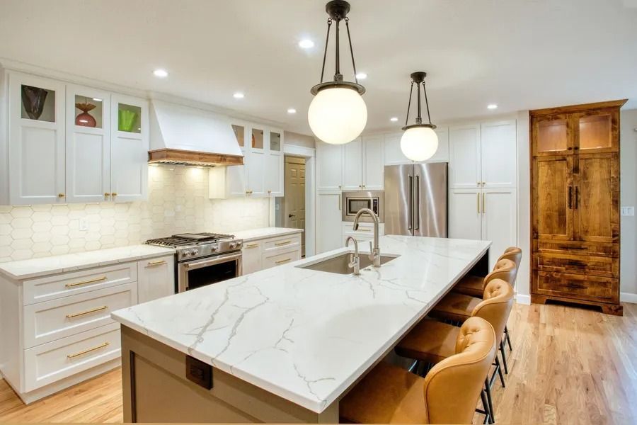 Modern kitchen with white cabinets, large island, pendant lights, and wooden floor.
