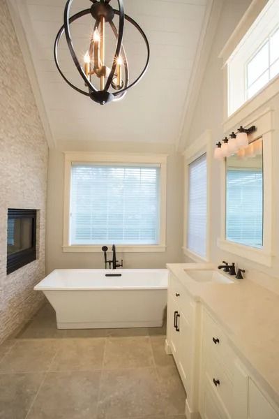 Modern bathroom with a white tub, vanity, and a mosaic tiled wall with a fireplace.