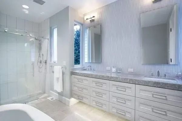 Modern, light-toned bathroom with glass shower, double vanity, and large mirror.