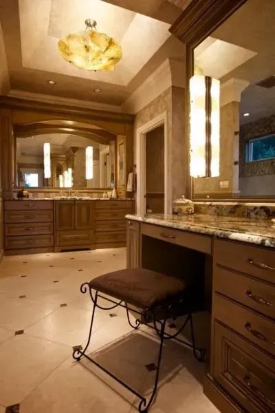 Luxurious brown bathroom with vanity, stool, and large mirror. Marble floor, warm lighting.