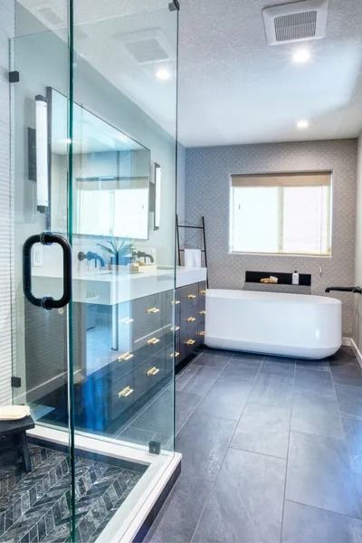 Modern bathroom with a glass shower, soaking tub, and gray tile floor.
