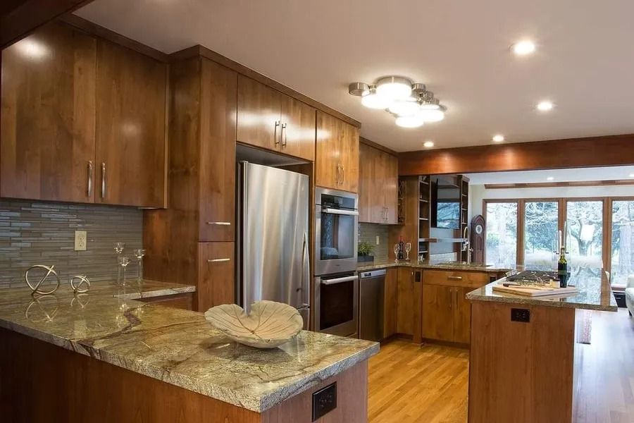 Kitchen with wooden cabinets, stainless steel appliances, granite countertops, and a view of the outdoors through a sliding glass door.