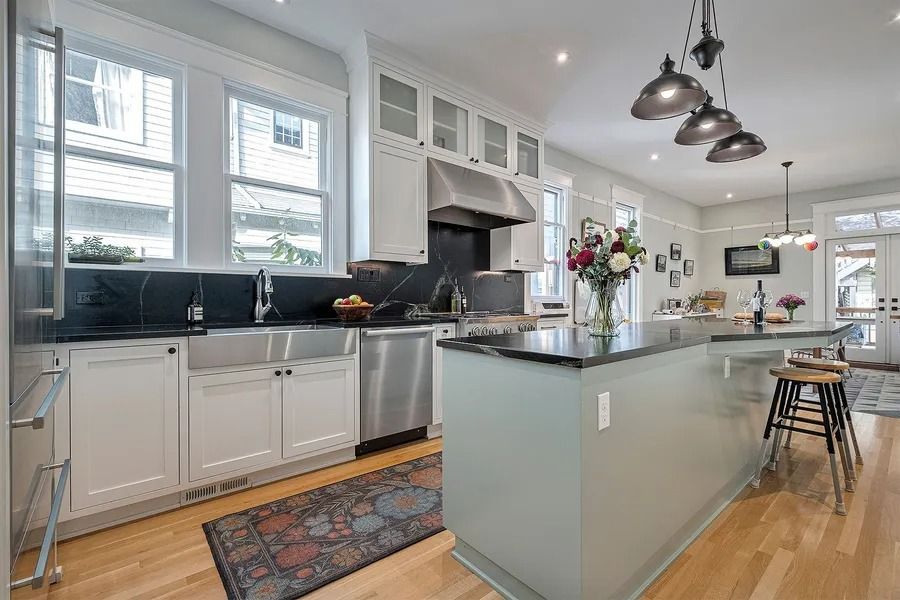 Modern kitchen with stainless steel appliances, dark countertops, and a gray island with seating.