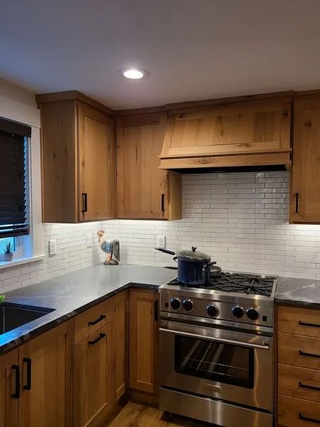 Kitchen with light wood cabinets, stainless steel appliances, and white tiled backsplash.