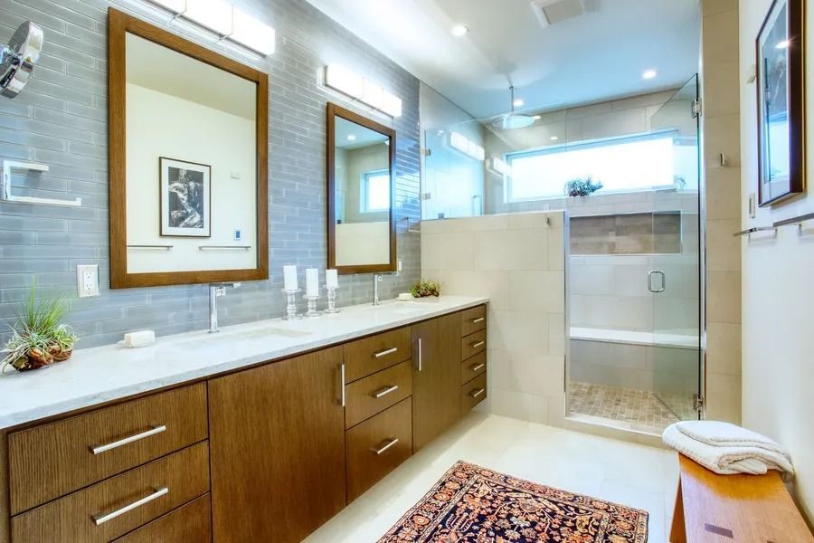 Modern bathroom with floating wood vanity, two mirrors, tiled walls, and a glass shower.