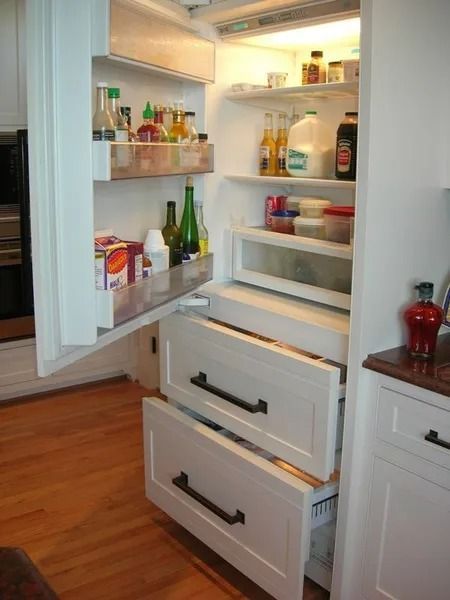 Opened refrigerator with drawers and shelves containing food items.