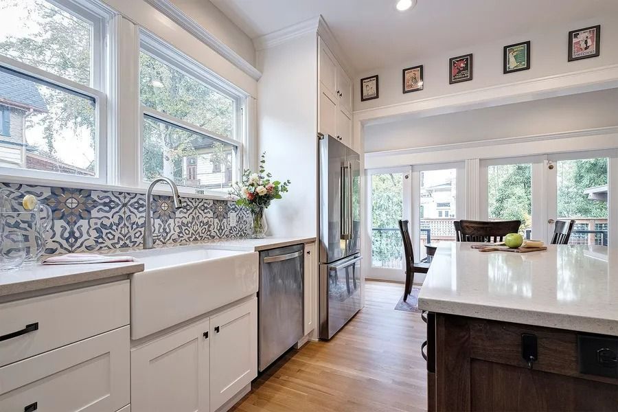 Bright kitchen with farmhouse sink, patterned backsplash, and stainless steel appliances.