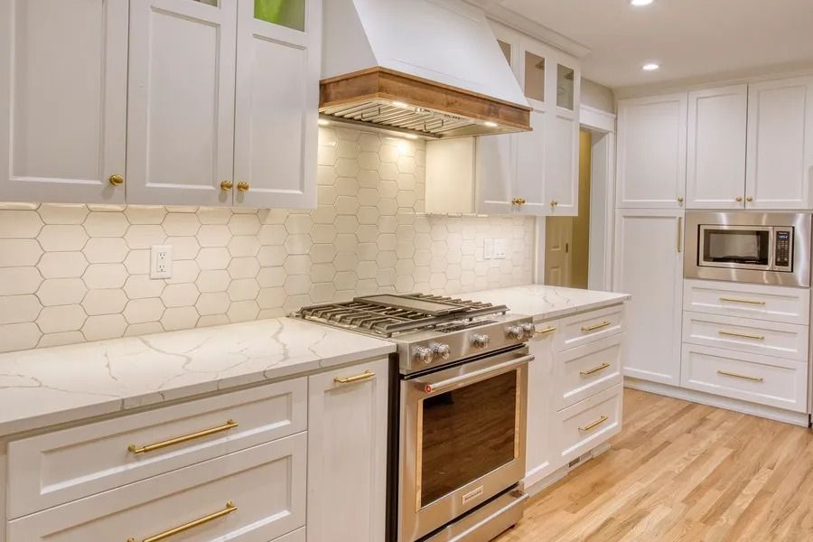 White kitchen with marble countertops, stainless steel appliances, and wood floors.