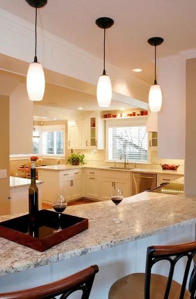 Kitchen with granite countertop bar, pendant lights, and two wine glasses.