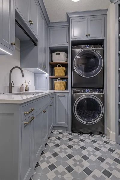Laundry room with gray cabinets, stacked black washer/dryer, patterned floor.