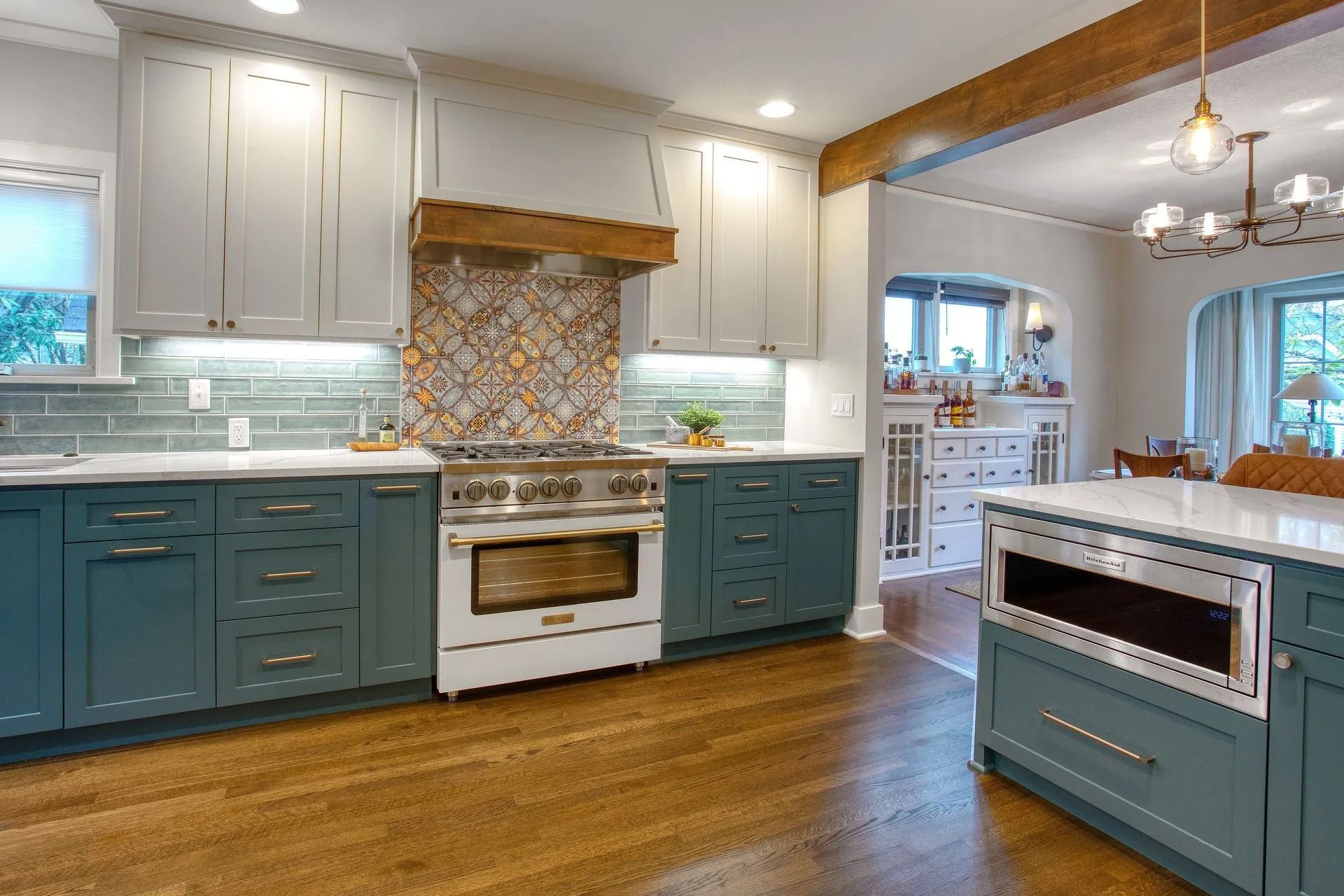 Two-toned blue and white kitchen with wood floors and patterned tile backsplash.