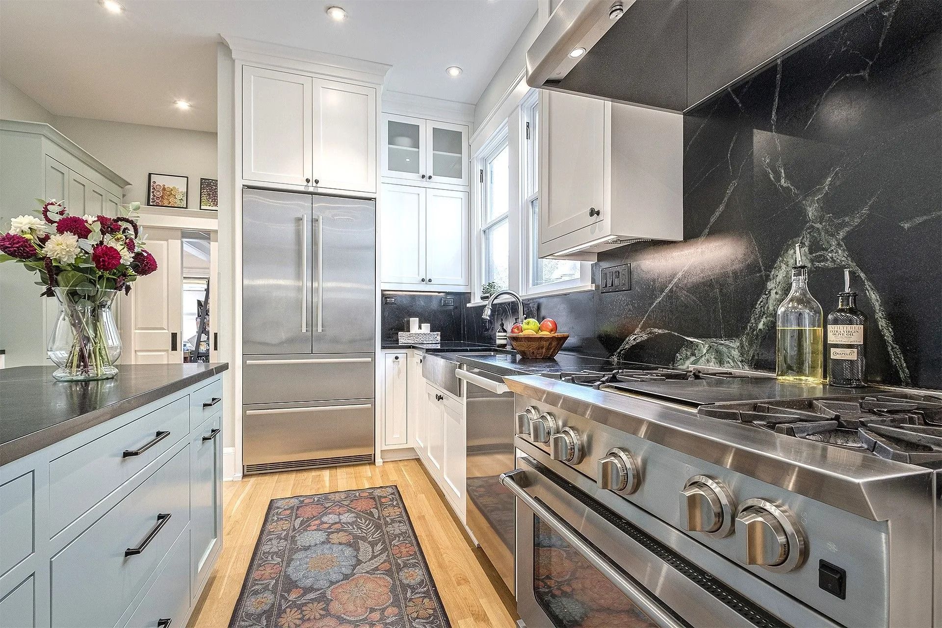 Modern kitchen with stainless steel appliances, white cabinets, and dark countertop and backsplash.