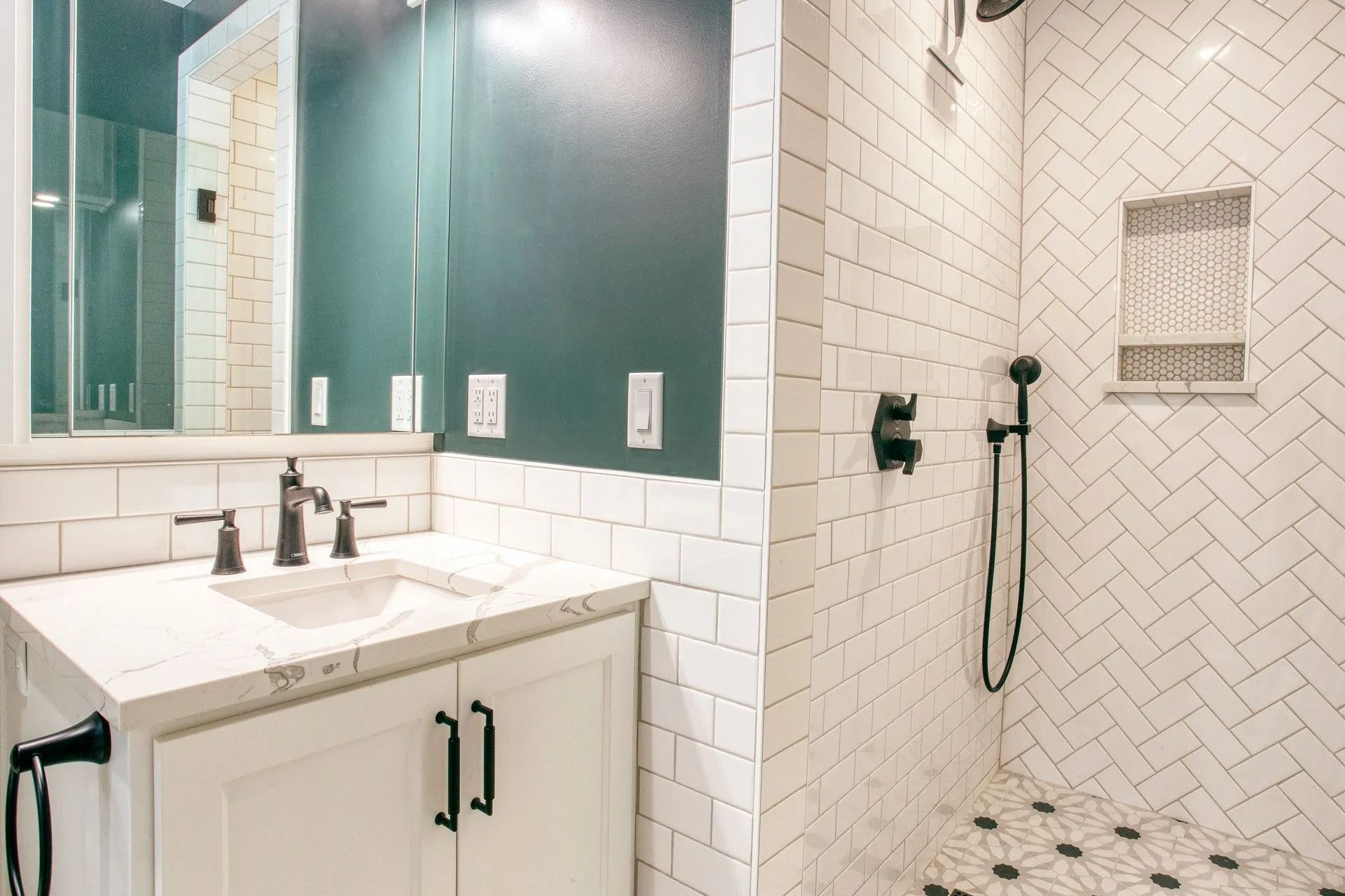 Bathroom with white subway tile shower, dark fixtures, white vanity, and dark green wall.