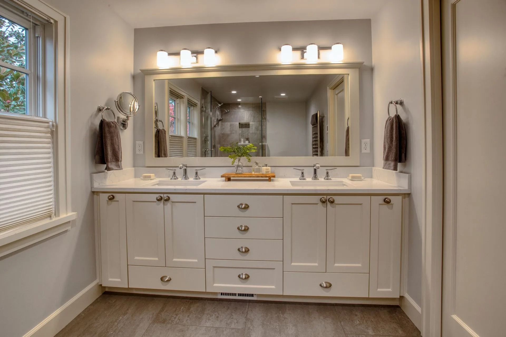 Bathroom with white double vanity, large mirror, and light fixtures.