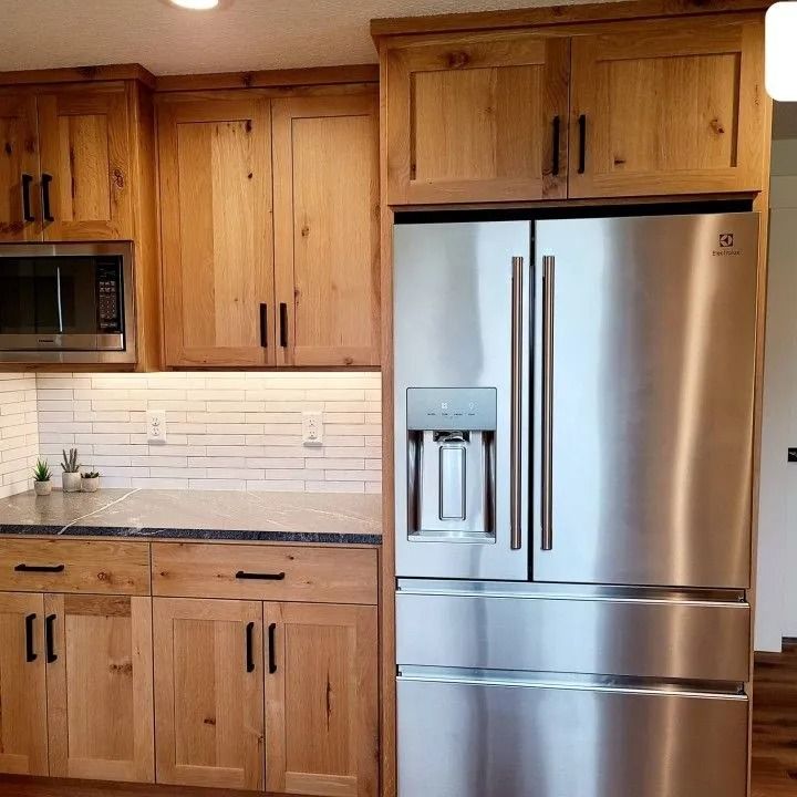 Kitchen with light wood cabinets, stainless steel refrigerator, and microwave.