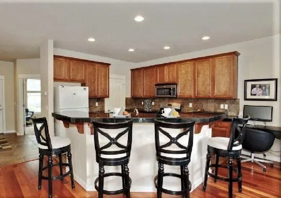 Kitchen with wood cabinets, black counter, and bar seating.