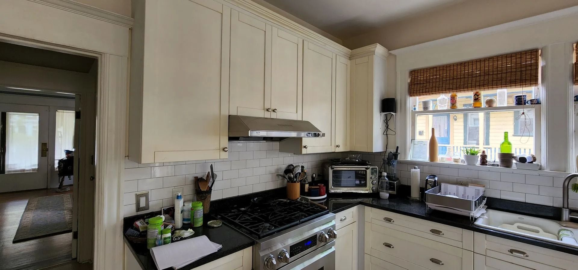 Kitchen with white cabinets, black countertops, and a window with a patterned valance.