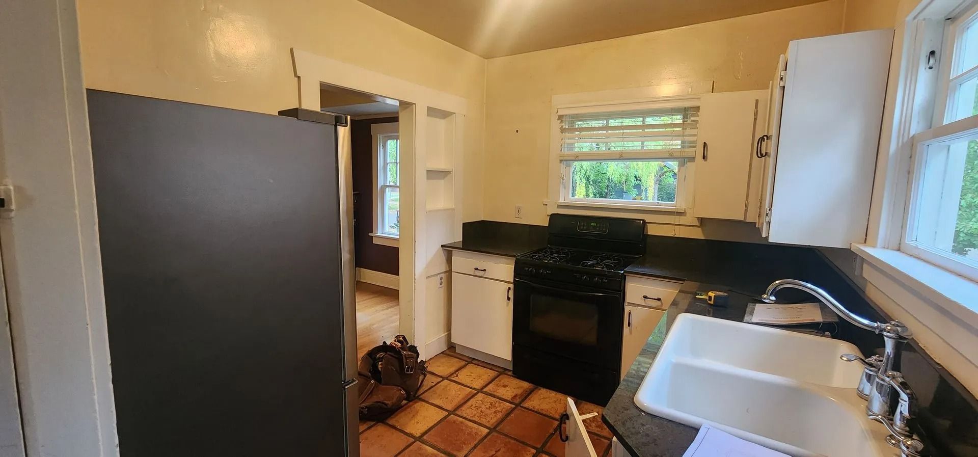 Kitchen with white cabinets, black stove and counter, and a window.