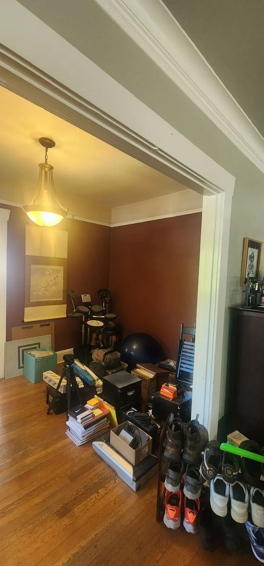 Cluttered room with wooden floors, piles of items, and shoe racks.