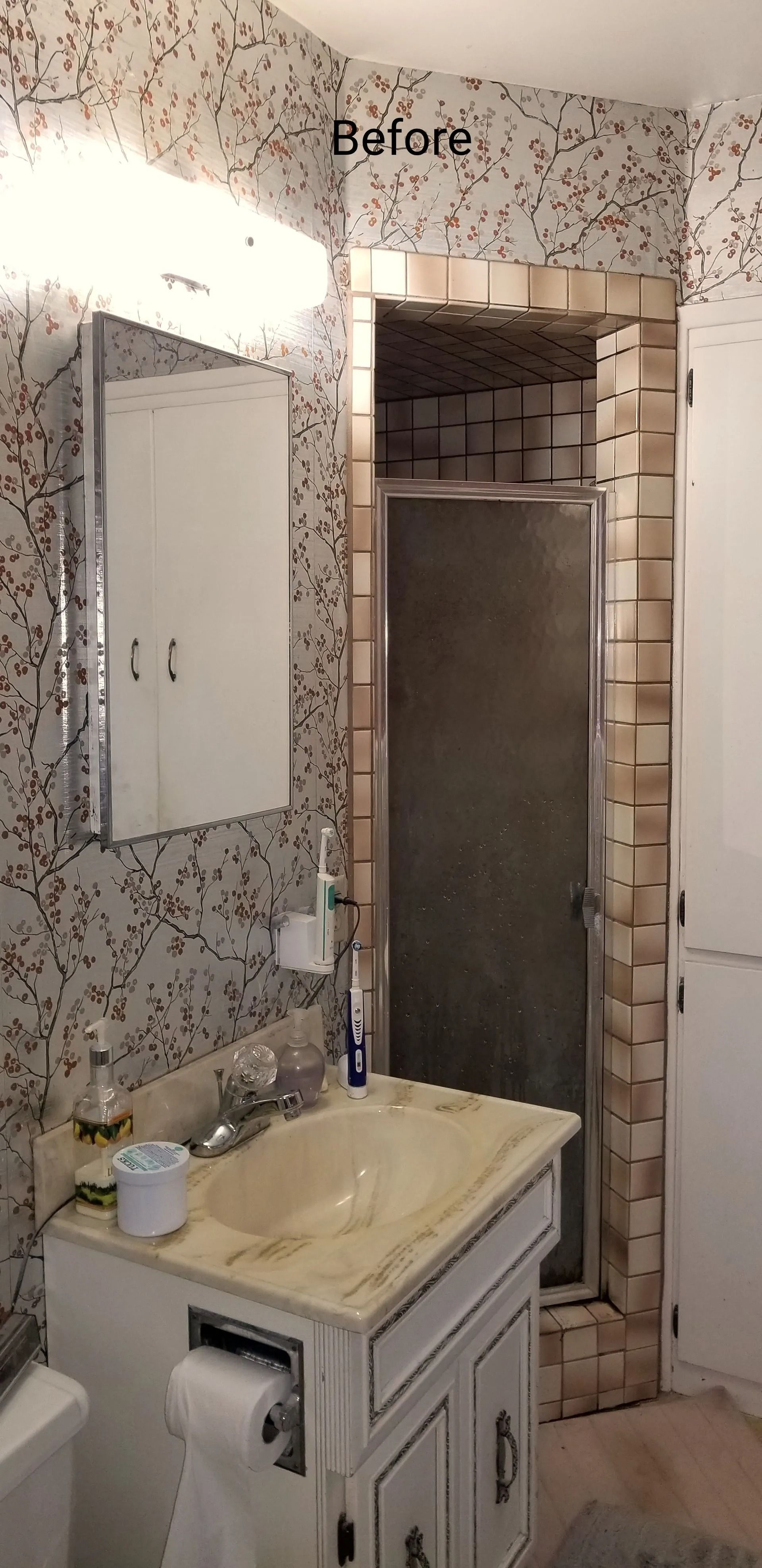 Small bathroom with a sink, mirror, shower, and patterned tile walls.