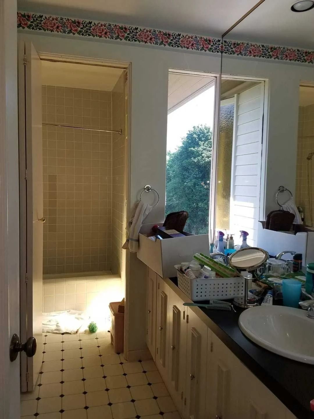 Bathroom with shower, vanity, window, and patterned tile floor.