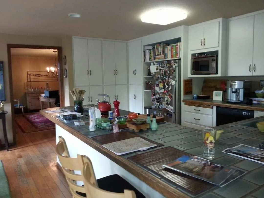 Kitchen with white cabinets, large island, stainless steel appliances, and wooden floor.