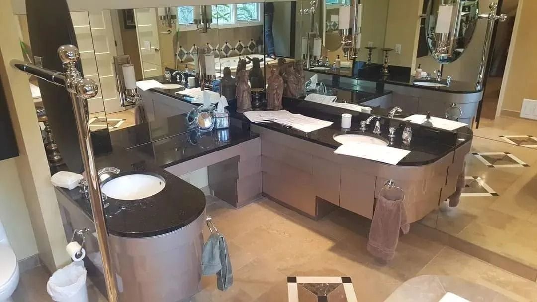 Spacious bathroom with black countertops, multiple sinks, and large mirrors. Beige walls and floor.