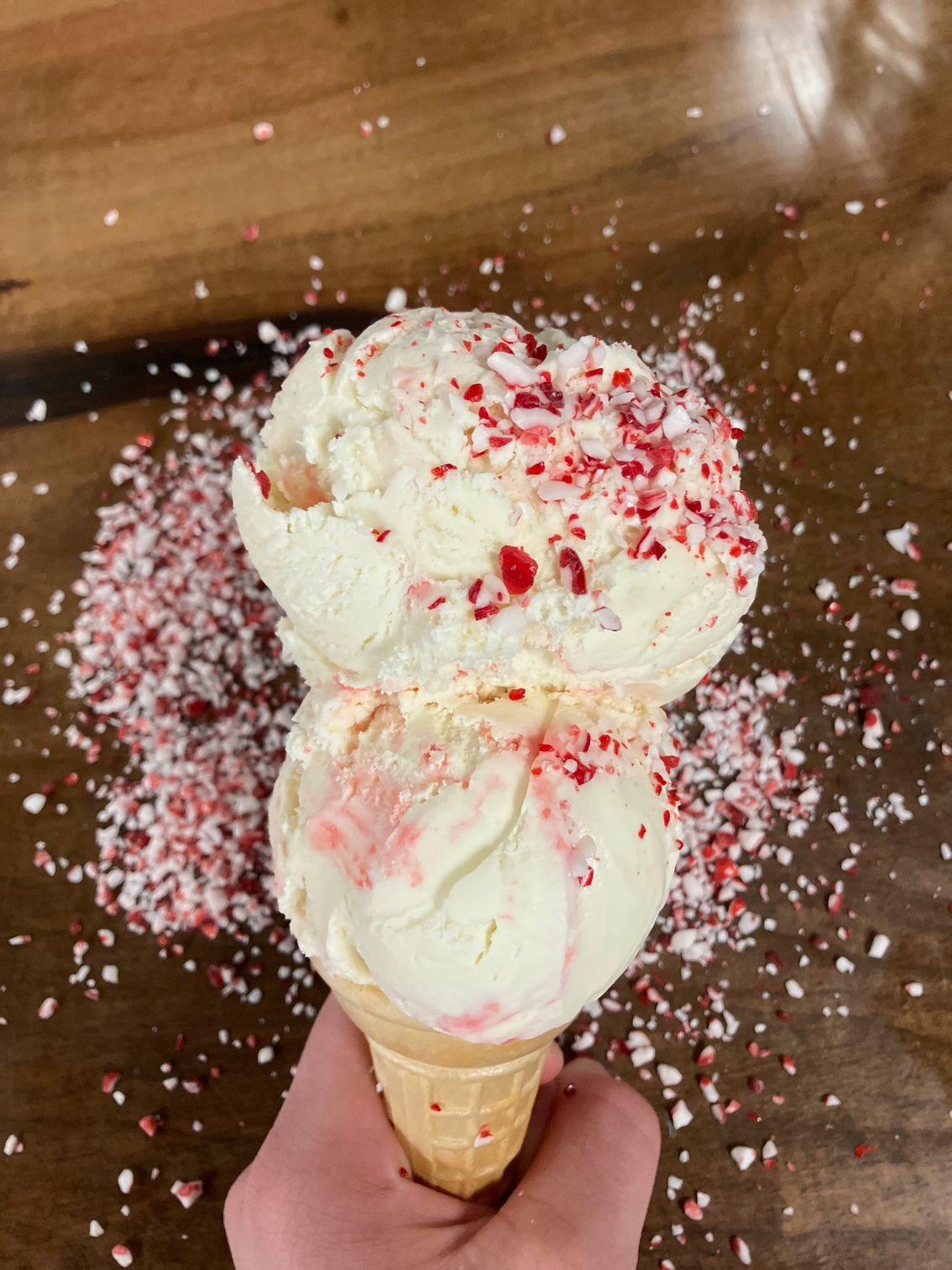 A person is holding two scoops of ice cream in a cone