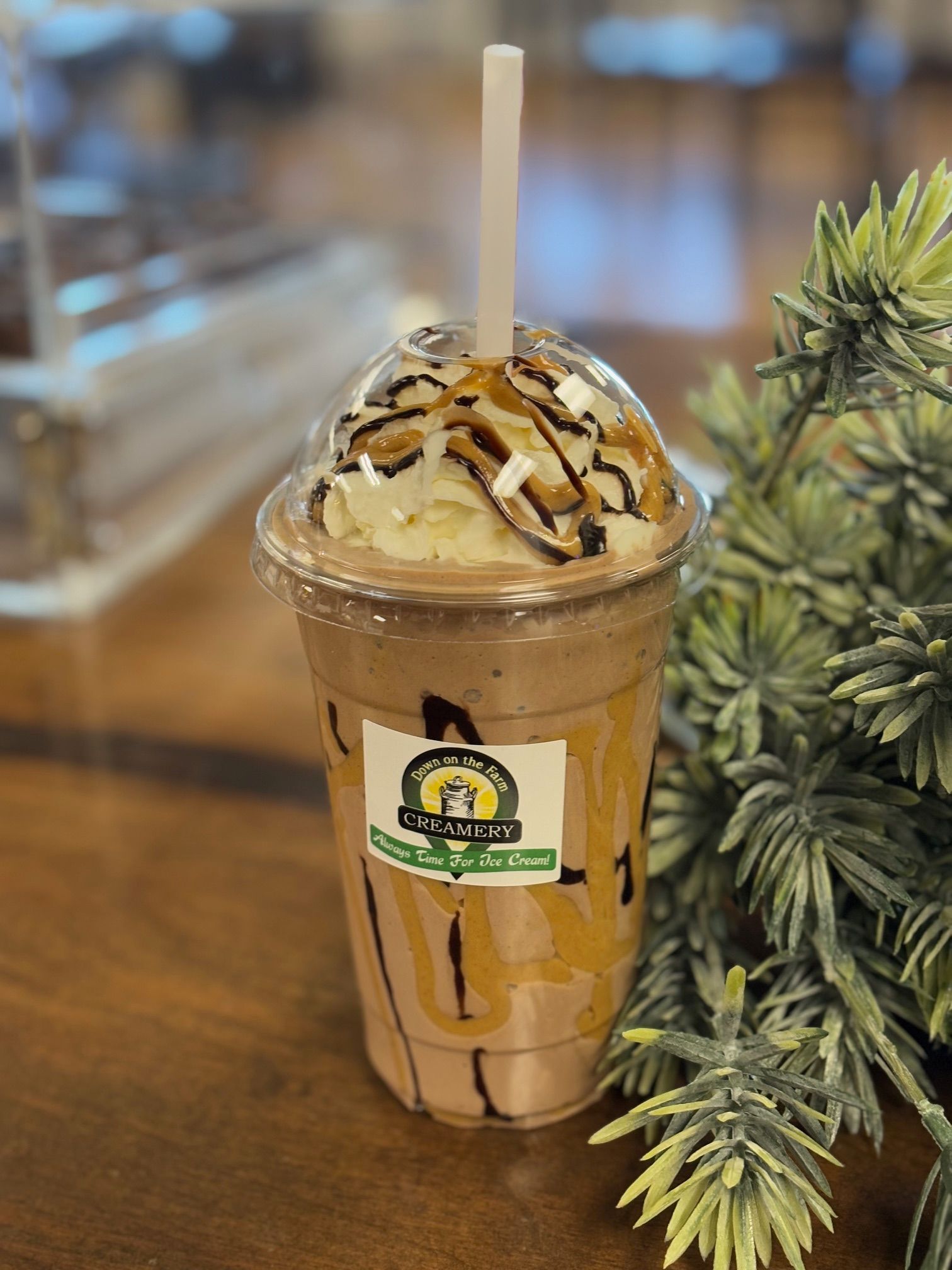 A close up of a milkshake with a straw on a table.