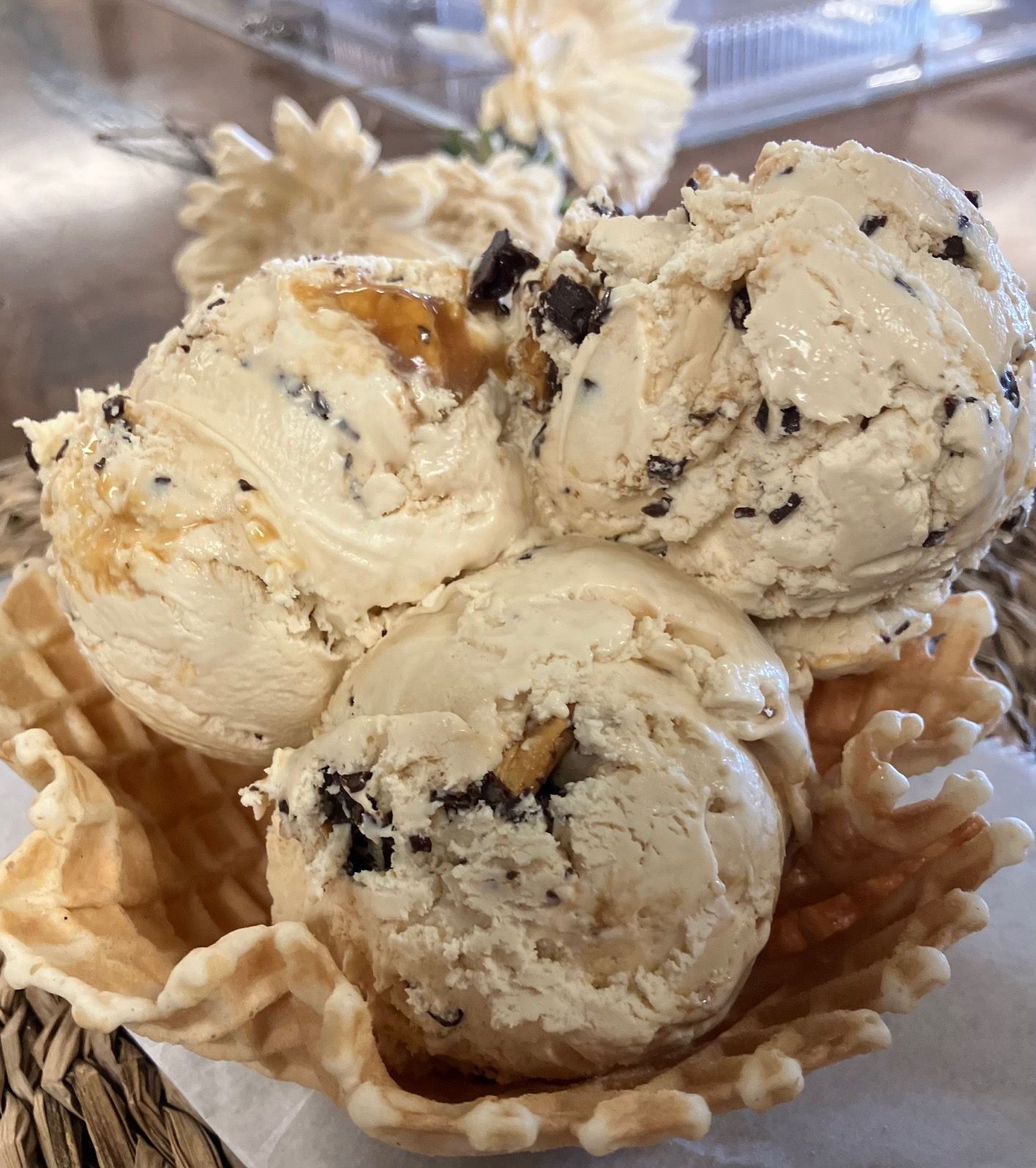 Three scoops of ice cream in a waffle cone on a table.