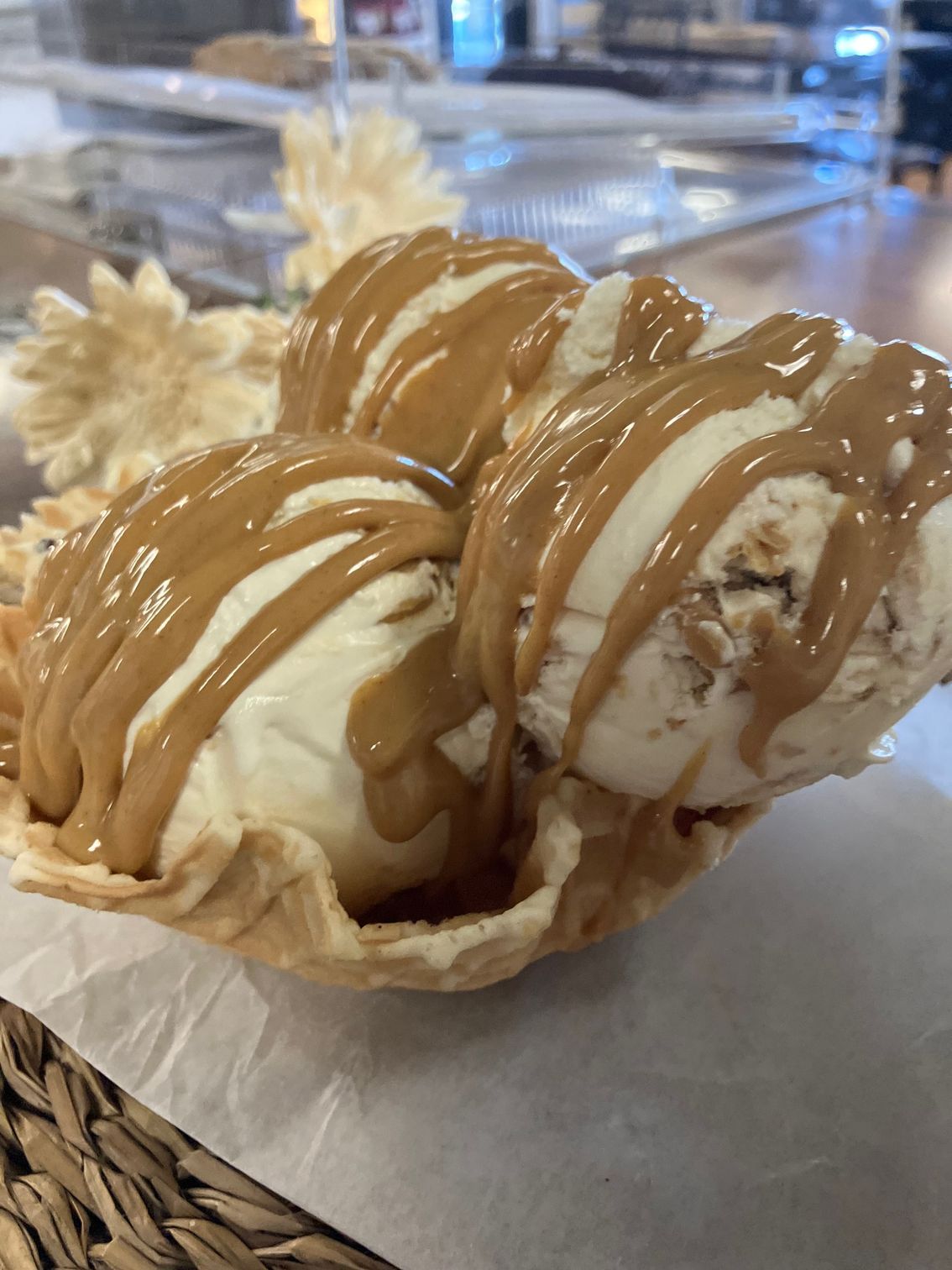 Two scoops of ice cream in a waffle cone with caramel sauce.