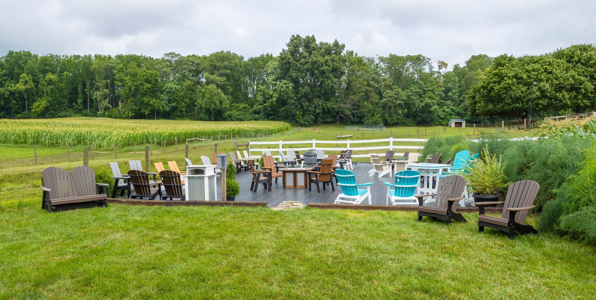 A bunch of chairs and tables are sitting on top of a lush green field.